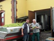 Herr Henke und Kellermeister Doedtmann stehen vor Edelstahlbehäler mit Trauben im Hof des Weingutes