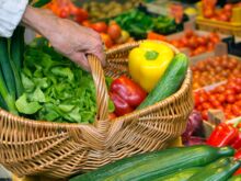 Symbolfoto Einkaufen - Hand hält Korb mit Gemüse