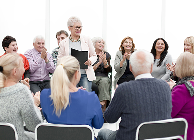 Senioren sitzen im Kreis und klatschen Vortragender zu
